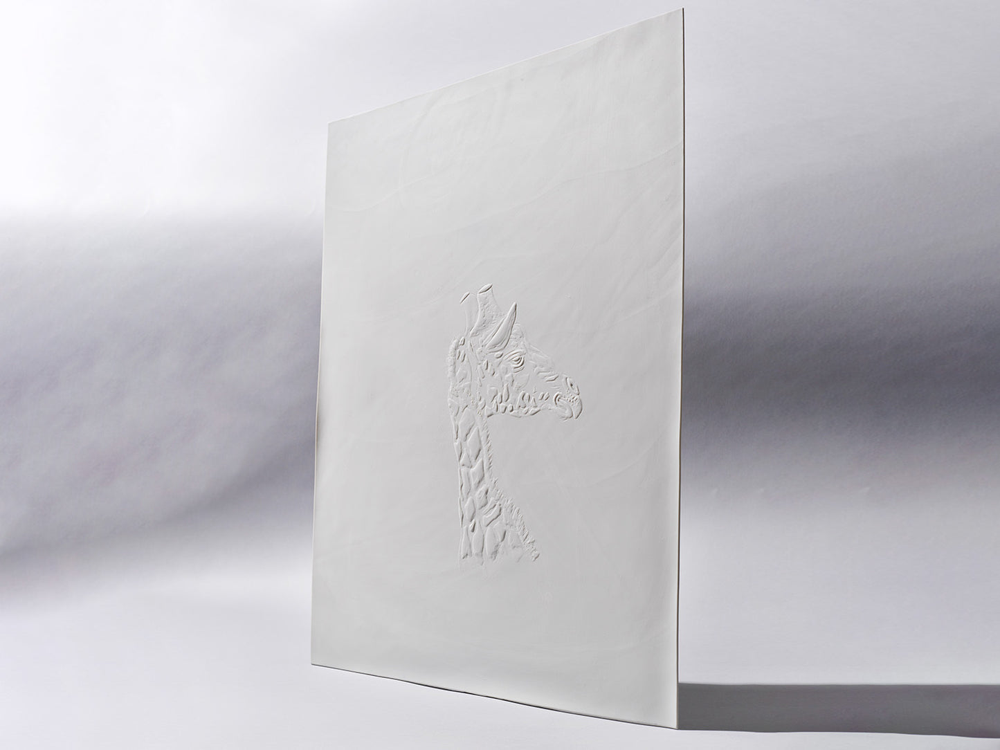 Aufrecht stehende Biskuitporzellanfliese in Weiß mit einem plastisch ausgearbeiteten Giraffenkopf im Profil. Die matte Oberfläche unterstreicht die feine Reliefstruktur.