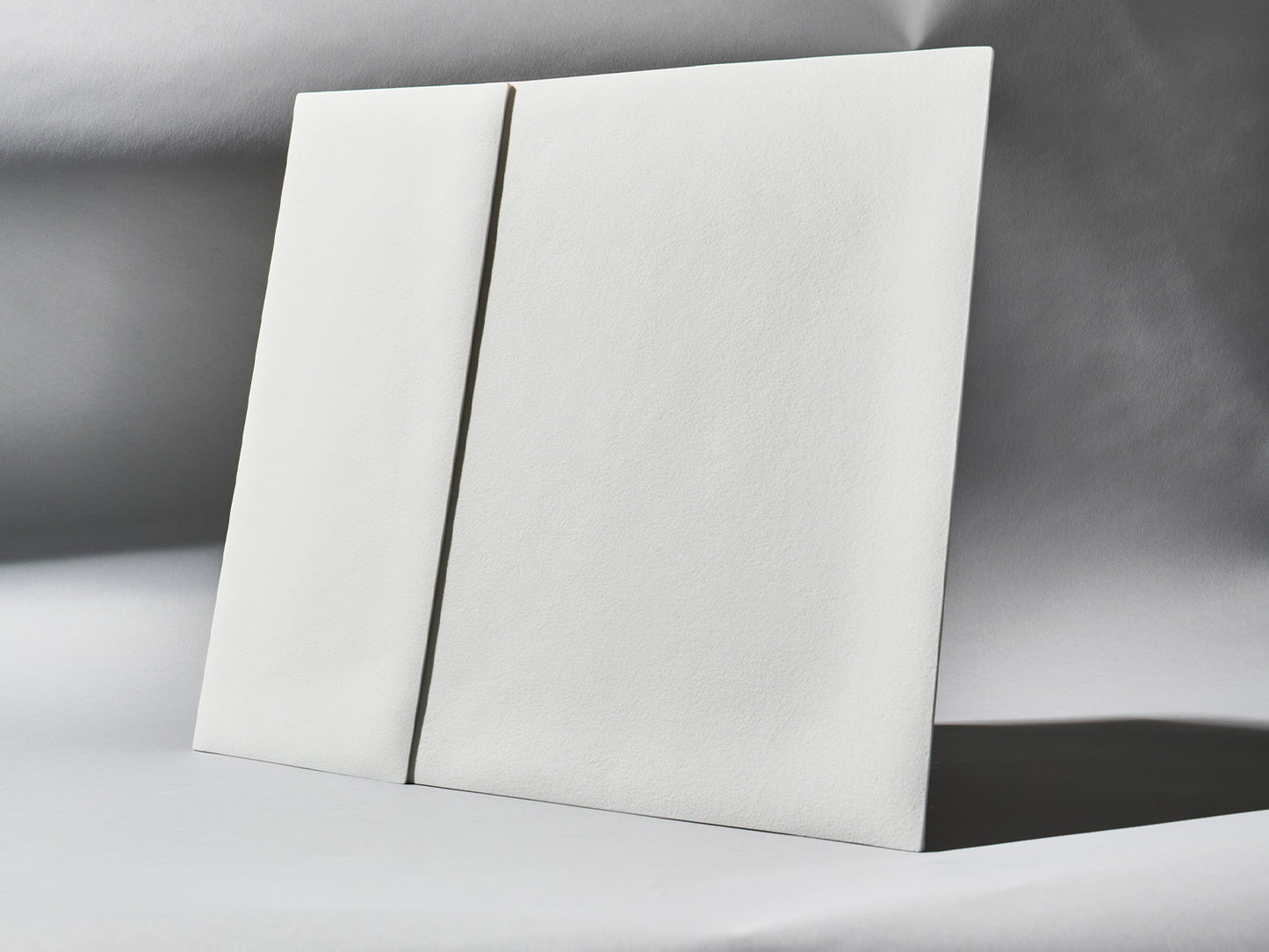 Unglasierte Porzellanfliesen der Serie Lightscape, schräg aufgestellt, mit sanftem Lichtverlauf über der strukturierten Oberfläche.
Unglazed porcelain tiles from the Lightscape series, placed at an angle, with soft lighting across the textured surface.