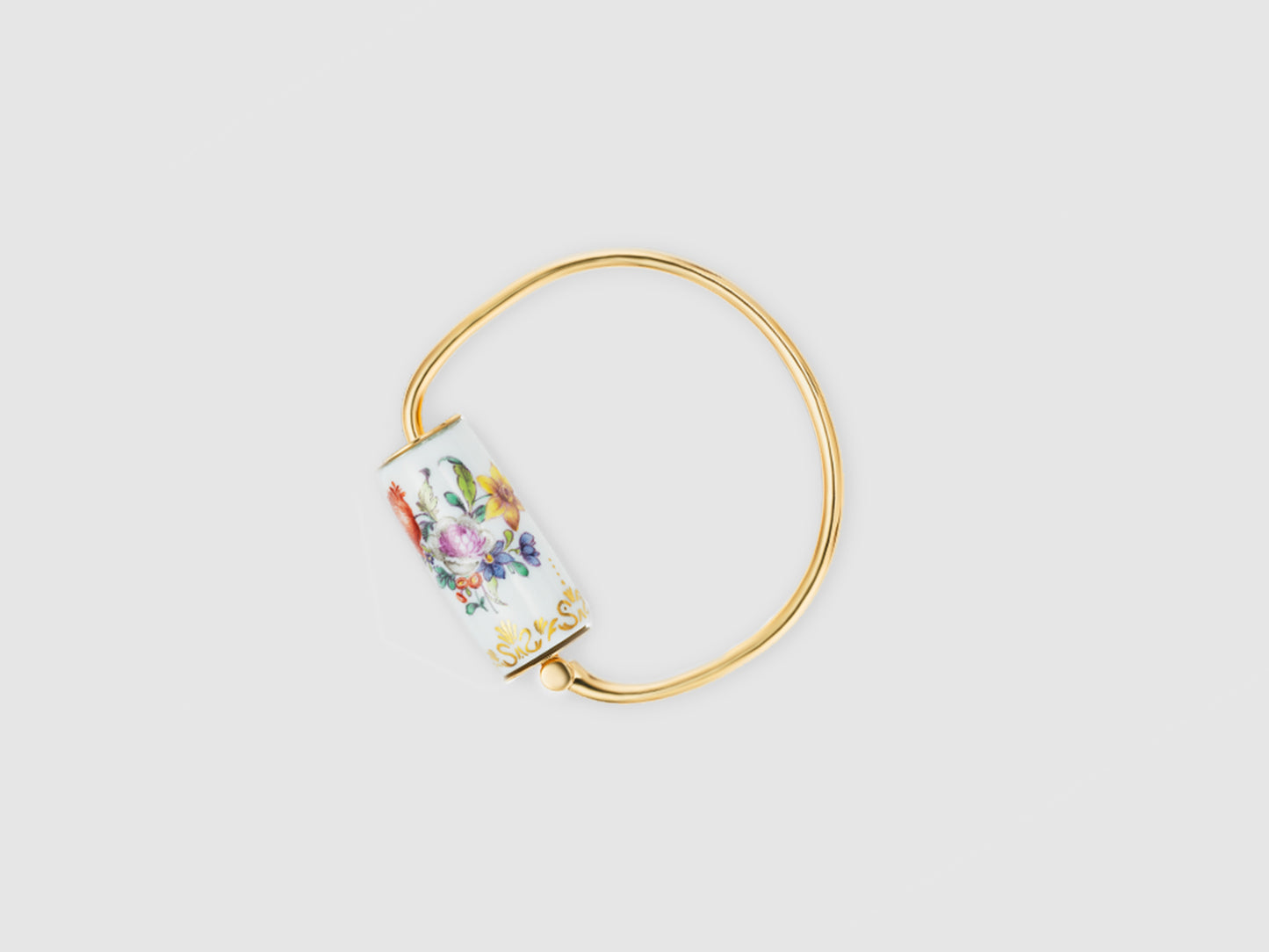 Alt (DE): Goldfarbener Armreif mit zylindernem Porzellan-Element, handbemalt mit buntem Blumenbouquet auf weißem Grund.
Gold-toned bangle with a cylindrical porcelain element, hand-painted with a colorful floral bouquet on white.