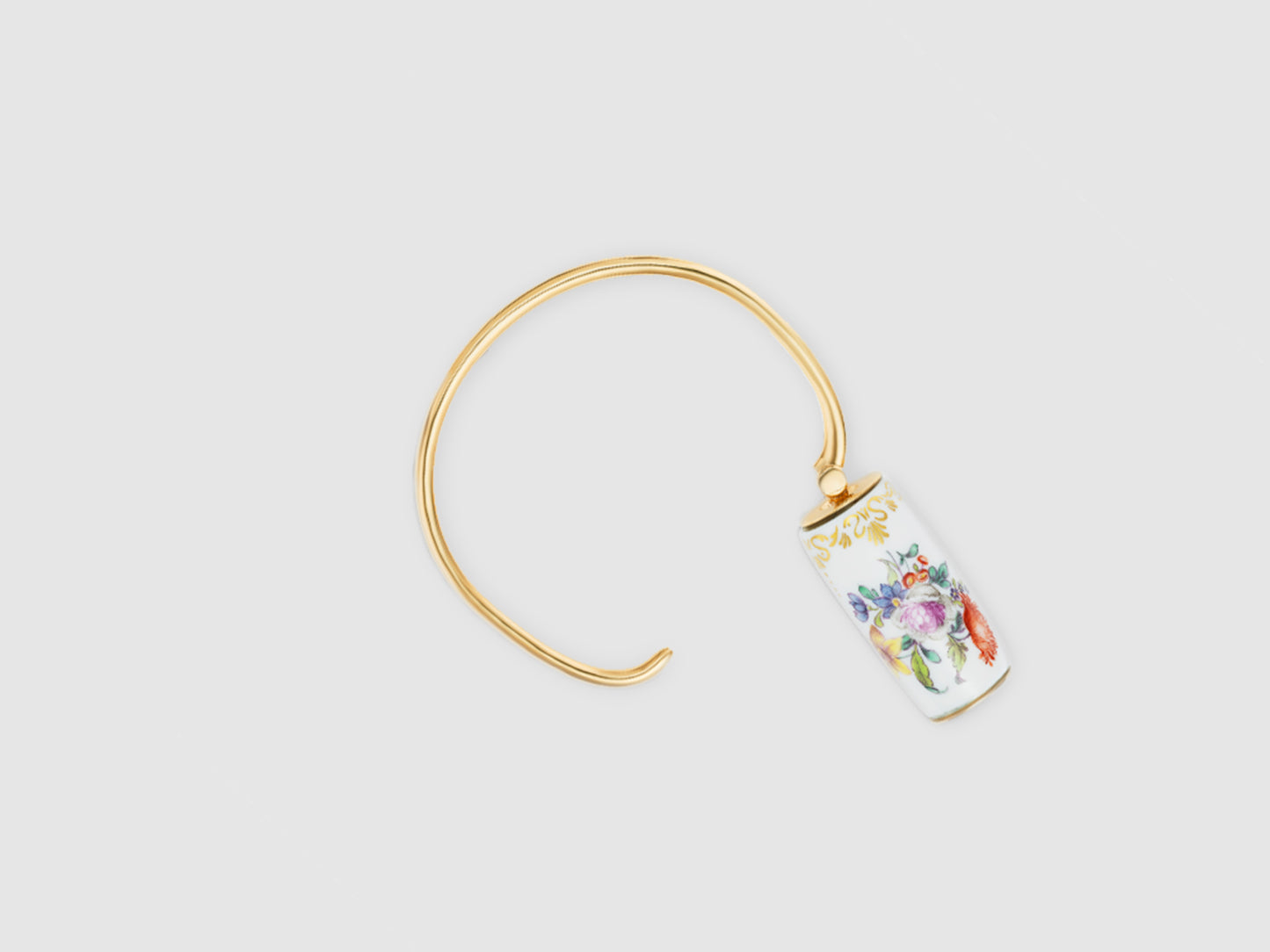 Geöffneter Armreif mit drehbarem Porzellan-Zylinder und goldfarbenem Verschluss.
Open bangle showing the rotating porcelain cylinder and gold-toned closure.
