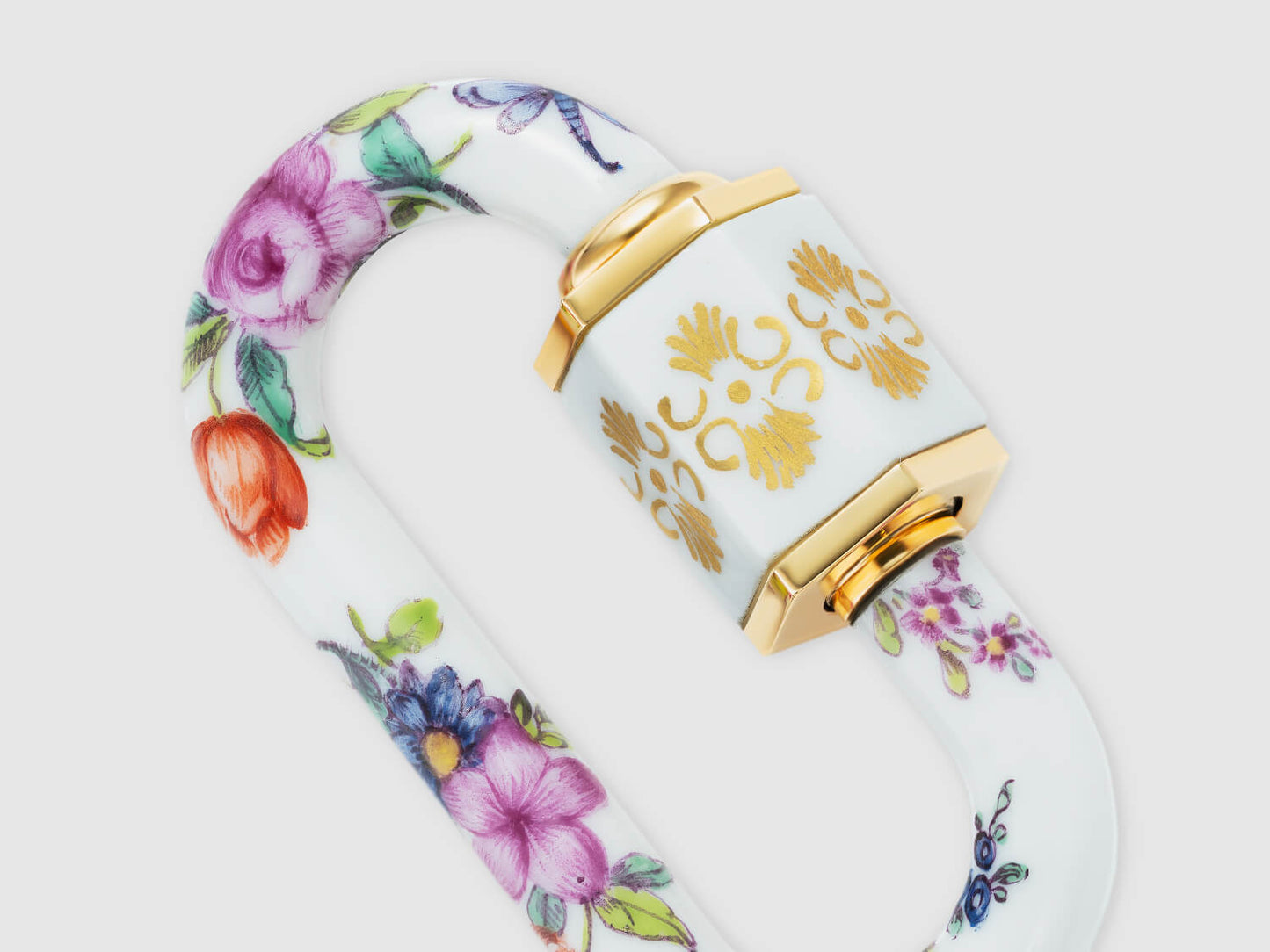 Detailaufnahme der vergoldet anmutenden Hülse mit Ornament und umlaufender Blumenmalerei auf dem Porzellan-Schloss.
Close-up of the gold-toned ornamental sleeve with continuous floral painting on the porcelain lock.