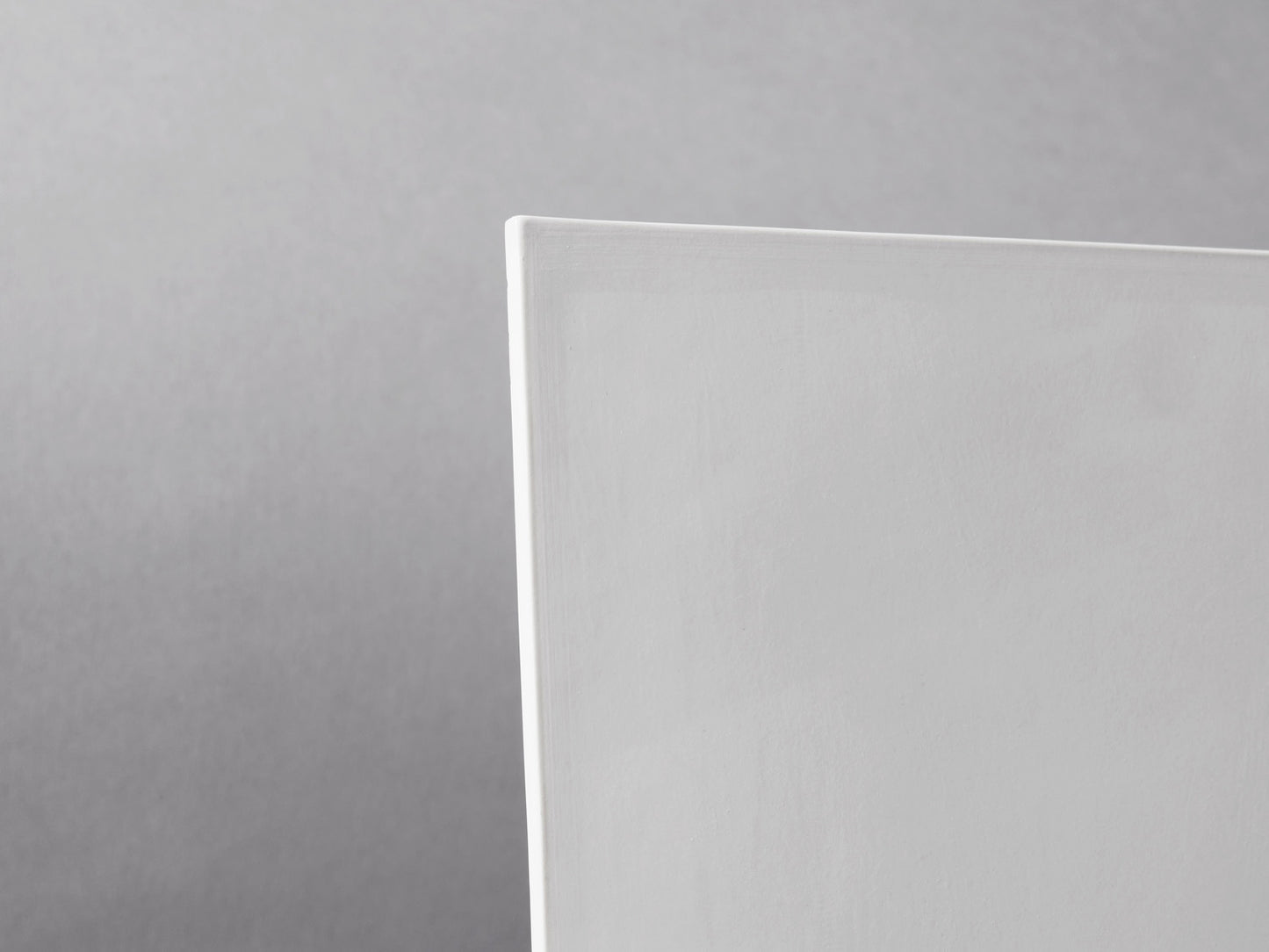 Detailansicht der oberen Ecke einer weißen Biskuitfliese.
Detail of upper corner of a white biscuit tile.
