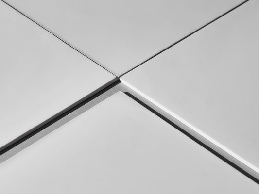 Nahaufnahme der Fugen vier weißer Fliesen.
Close-up of grout line between four white tiles.