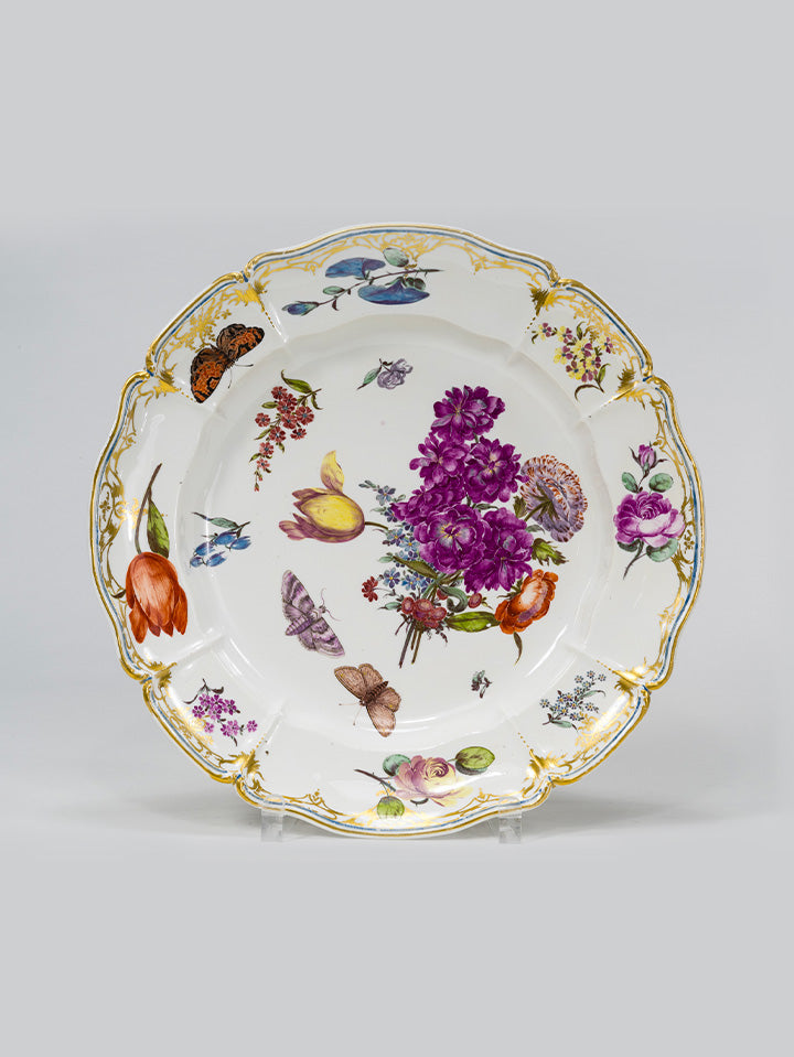 Porzellanteller mit floraler Malerei, goldverziertem Rand und filigranen Schmetterlingen.
Porcelain plate with floral motifs, gilded rim, and delicate butterflies.