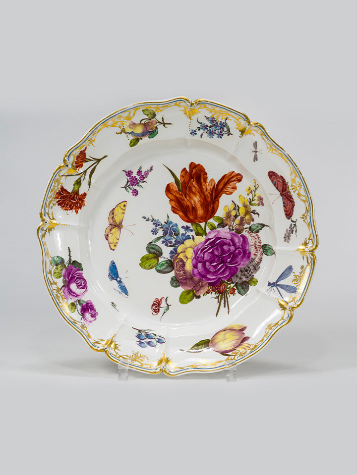 Porzellanteller mit barocker Blumenmalerei und goldverziertem Rand, verziert mit Insektenmotiven.
Porcelain plate with baroque floral painting and gilded rim, decorated with insect motifs.
