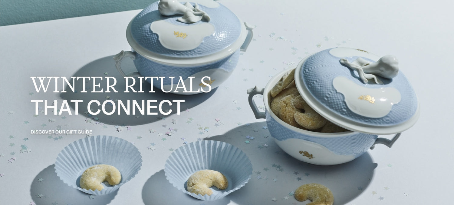 Light blue lidded porcelain bowls with animal finials filled with crescent cookies on a star-scattered surface, with the headline “Winter rituals that connect”.