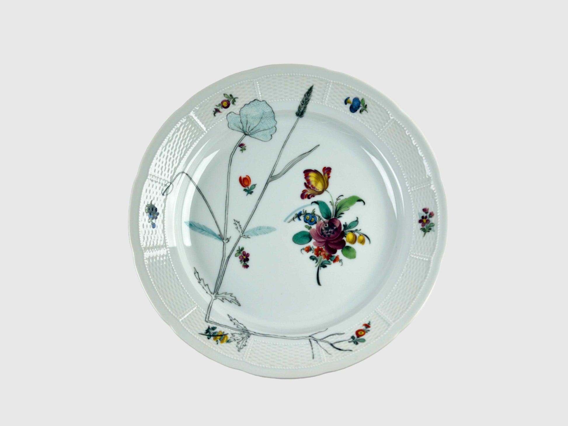 Runde Platte mit leicht gewelltem Rand und feiner Korbrelief-Struktur. Die Mitte ziert ein farbenfrohes Blumenbouquet, ergänzt durch feine botanische Zeichnungen in Schwarz. Der Tellerrand ist mit kleinen, farbigen Blüten und Insekten dekoriert.

Round porcelain platter with a gently scalloped edge and fine basket-weave relief. The center features a colorful floral bouquet, complemented by delicate black botanical line drawings. The rim is adorned with small, colorful flowers and insects.