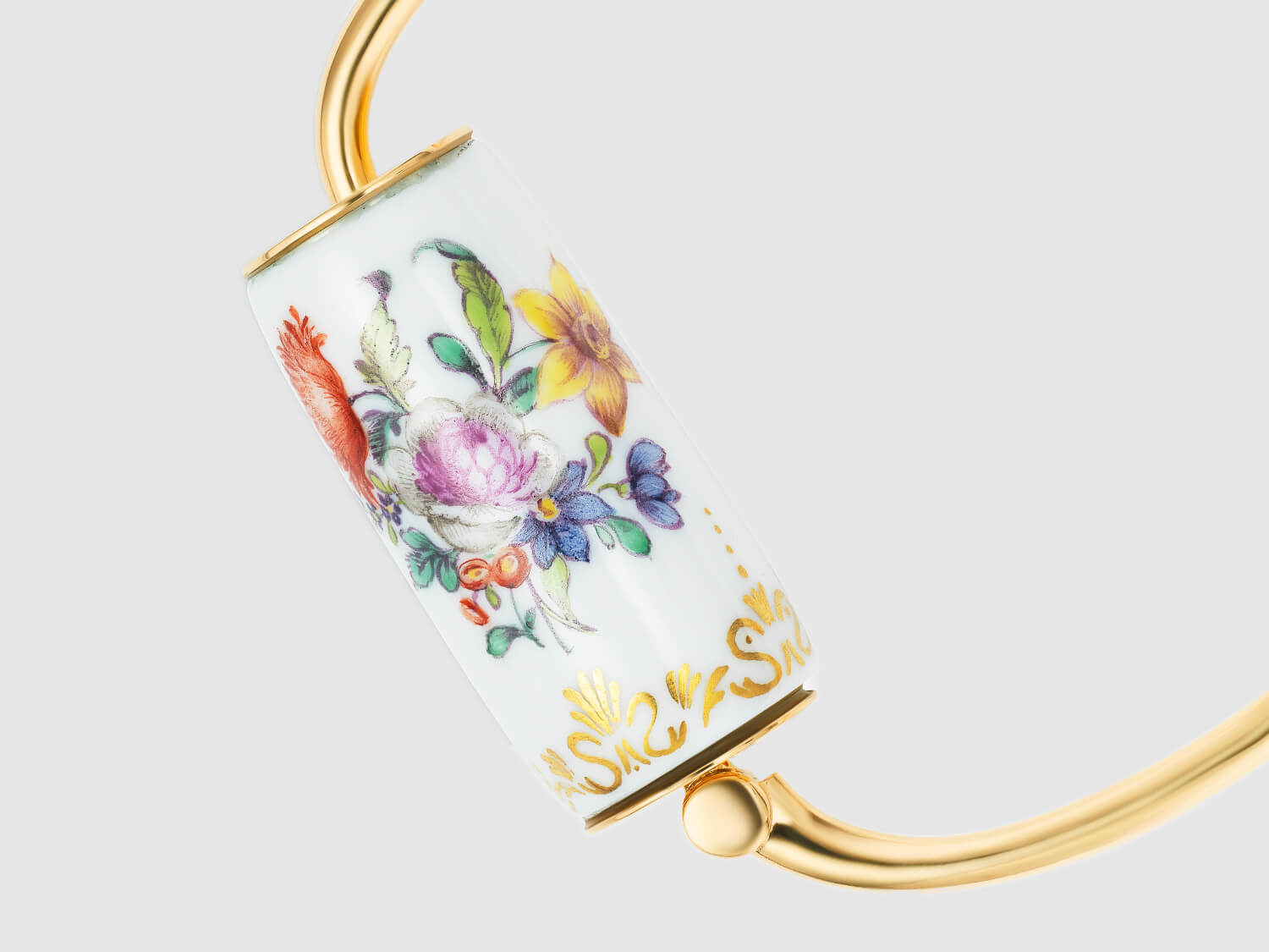 Detailaufnahme des Porzellan-Zylinders mit farbiger Blumenmalerei und goldfarbenen Rändern.

Detail view of the porcelain cylinder with colorful floral painting and gold-toned rims.