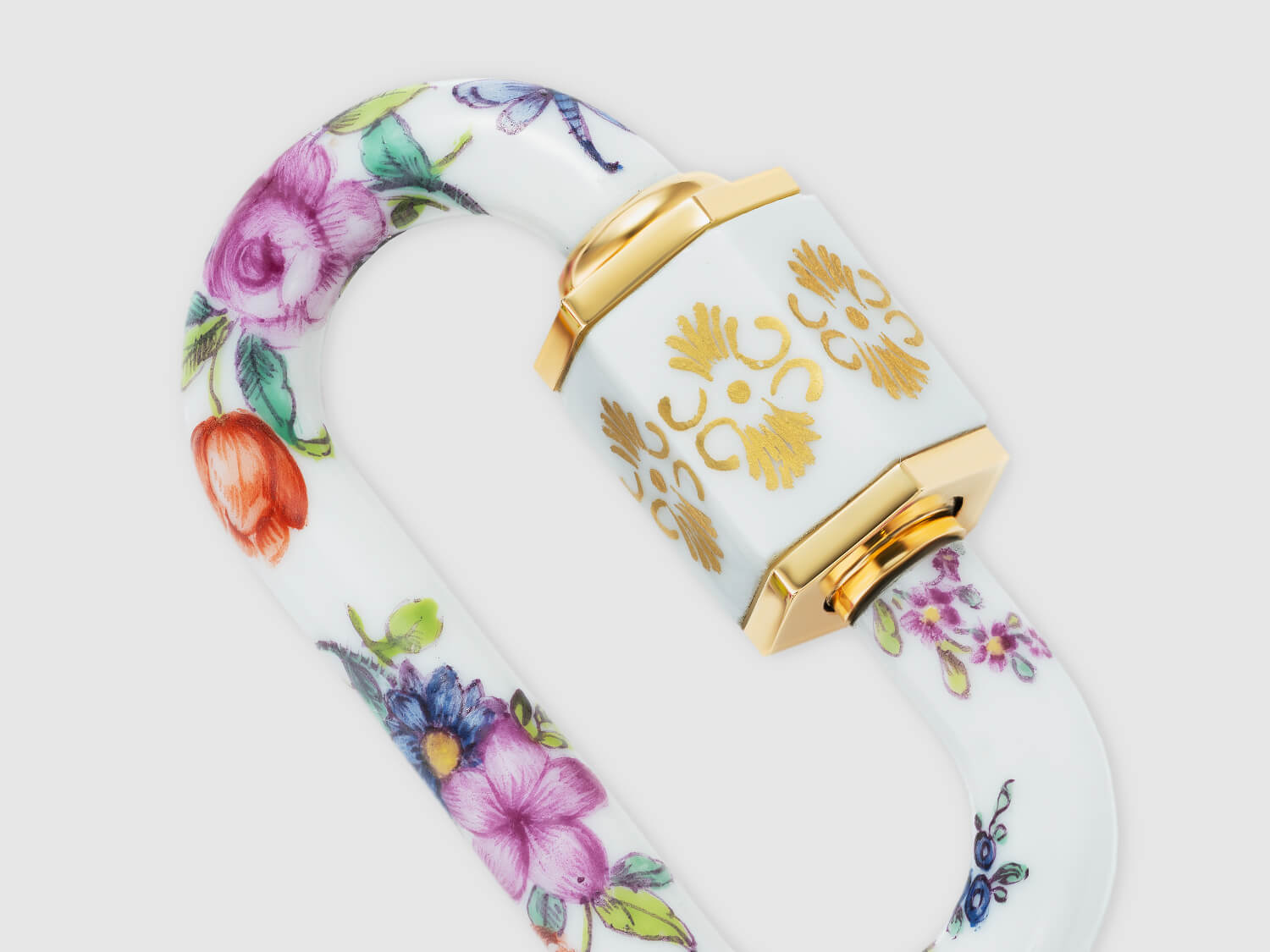 Detailaufnahme der vergoldet anmutenden Hülse mit Ornament und umlaufender Blumenmalerei auf dem Porzellan-Schloss.

Close-up of the gold-toned ornamental sleeve with continuous floral painting on the porcelain lock.