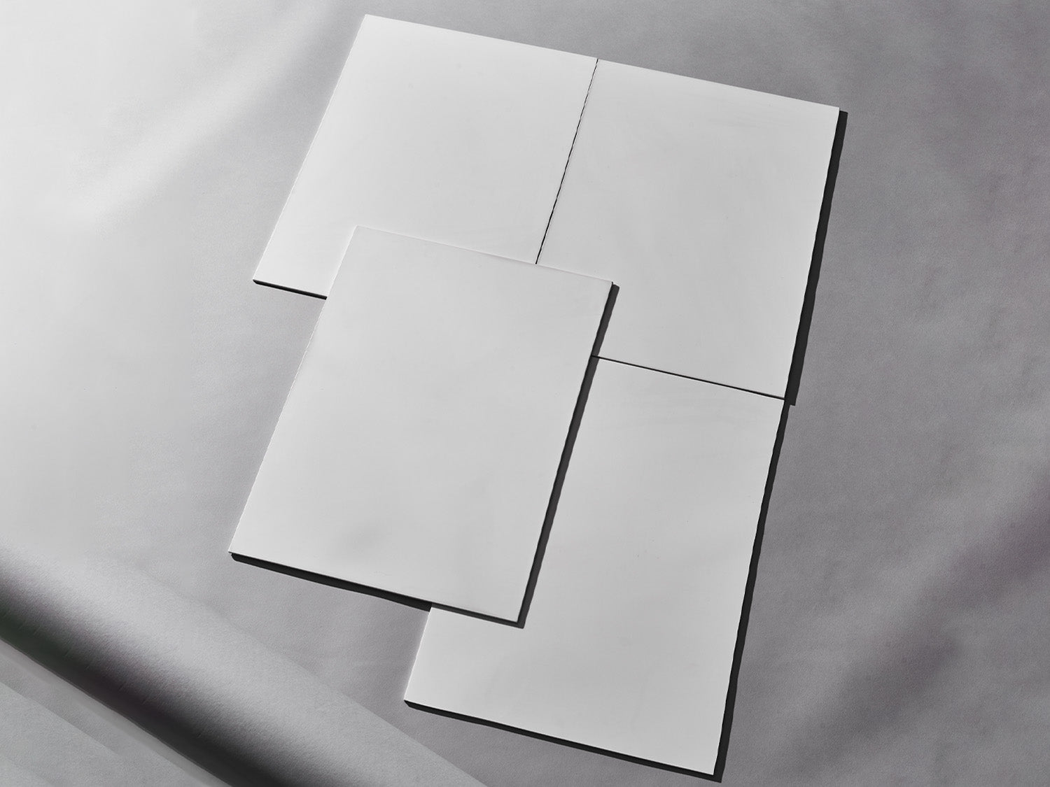 Vier weiße Fliesen auf grauem Hintergrund arrangiert.

Four white tiles arranged on grey background.