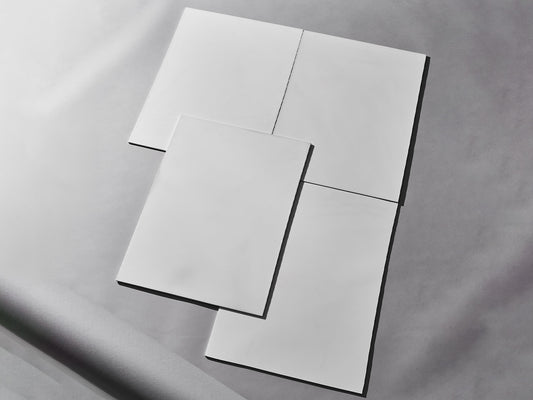 Vier weiße Fliesen auf grauem Hintergrund arrangiert.

Four white tiles arranged on grey background.