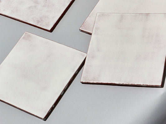 Majolika-Fliese mit durchschimmernder weißer Glasur und changierender Oberfläche.

Majolica tile with translucent white glaze and subtly shifting surface tones
